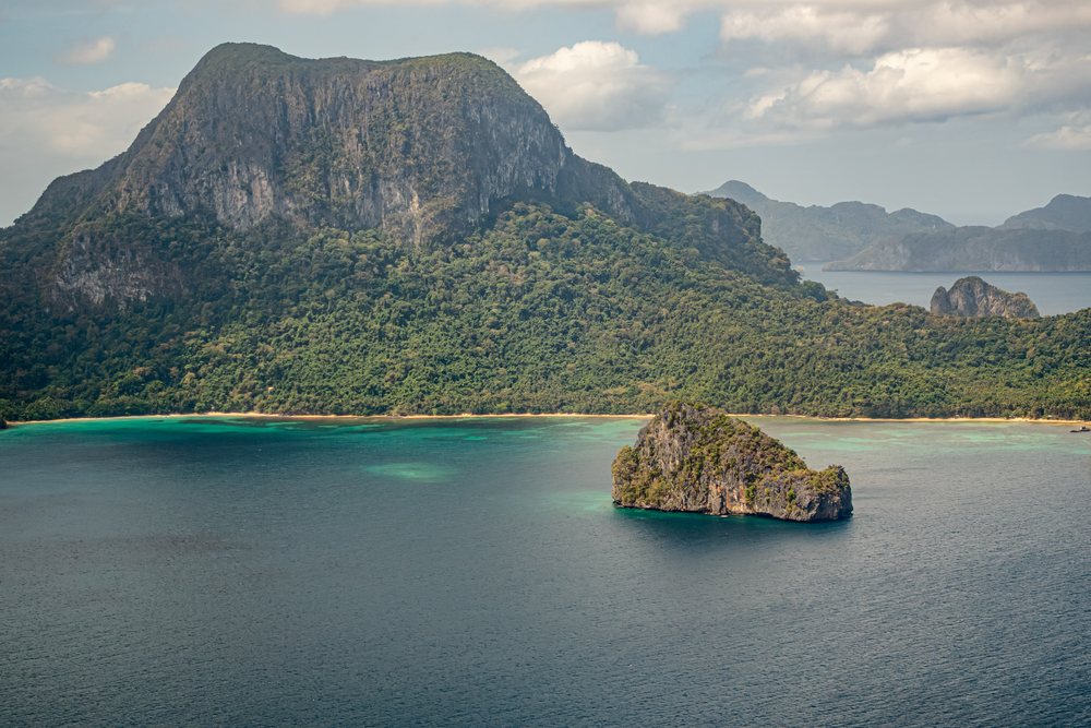 Island with steep rock formation and tropical trees, Philippines.