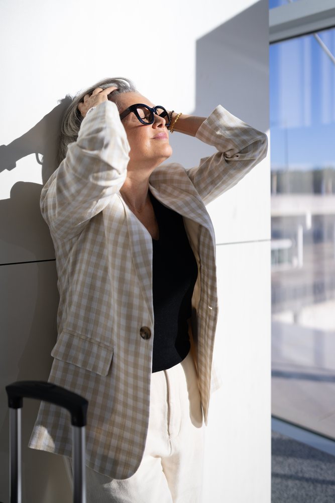 Woman business traveler standing and relaxing in a modern airport terminal with sunlight and reflections, Spain, Madrid.
