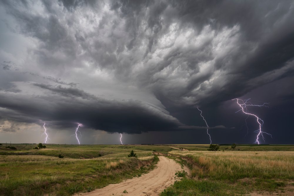 Lightning strikes over grassland with a dirt road during a thunderstorm, Storm Chasing, Wallace, Nebraska, USA.