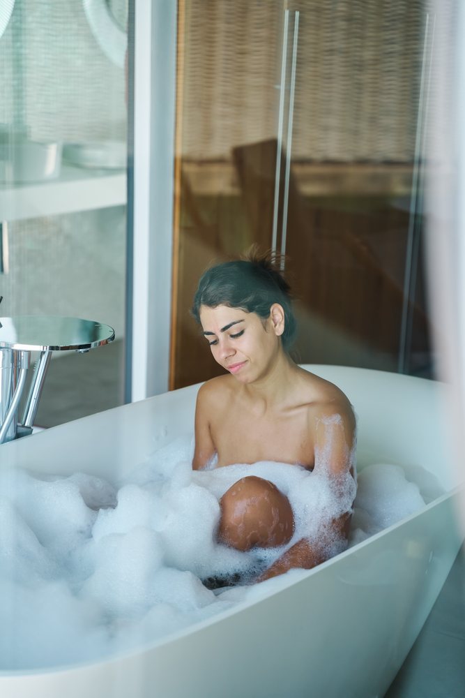 A woman enjoys a bubble bath in a modern bathtub inside a bathroom in the, Maldives.