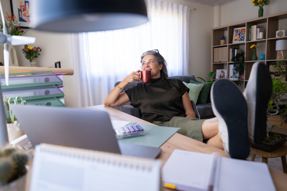 Woman sitting and relaxing with a coffee mug at a desk in a modern home office during the day, Spain.
