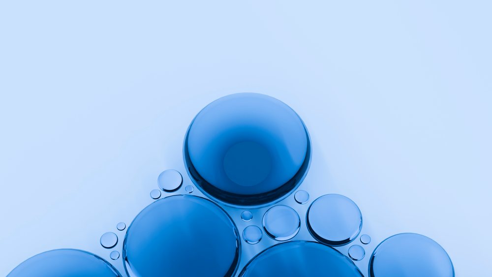 Multiple blue spherical bubbles clustered together on a light surface showing reflections and transparency.