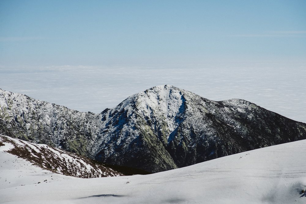 Snowy rocky mountain peak under a blue sky in a winter landscape, mountaineering, climbing, Spain.
