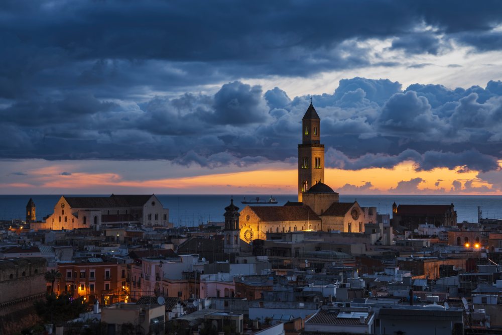 Bari Cathedral illuminated at Dawn overlooking the city and sea under a dramatic cloudy sky, Puglia, Italy.