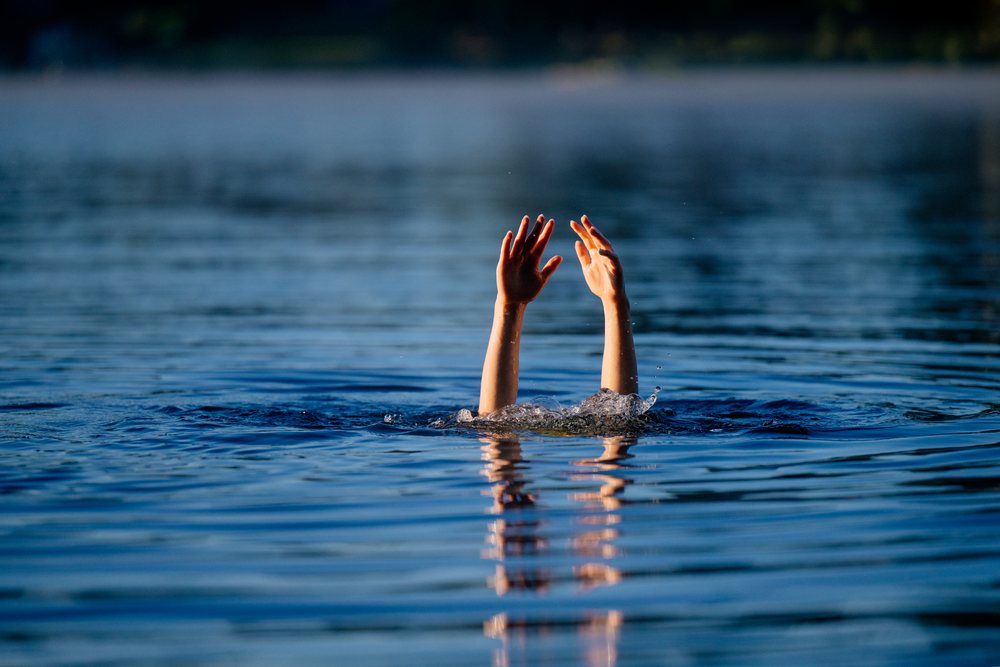 Arms raised above the surface of a freshwater lake with splashing water in a natural outdoor setting, USA.