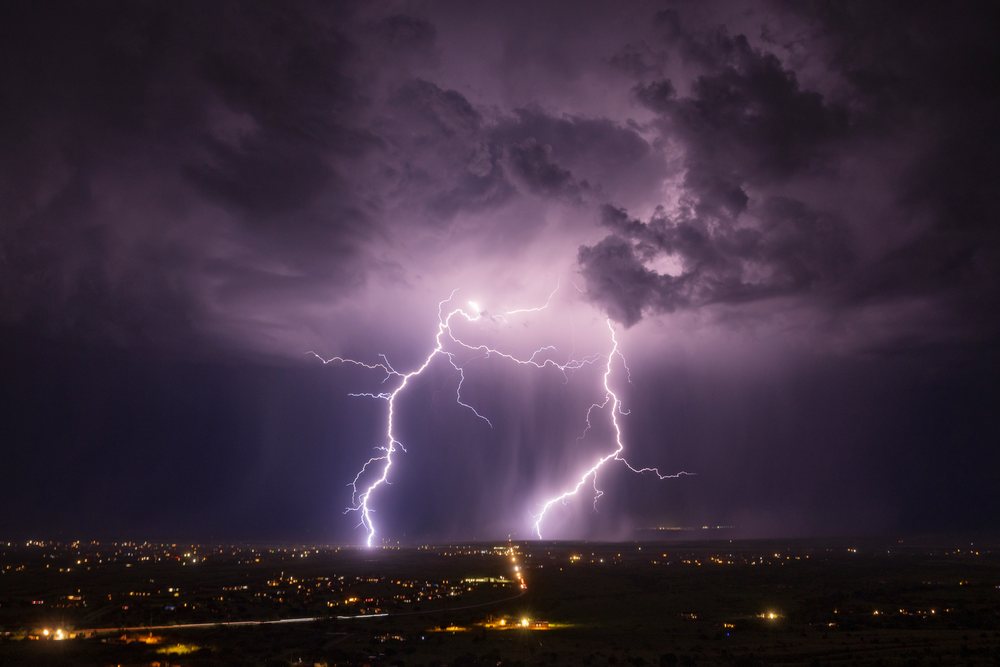 Lightning bolts illuminate dark storm clouds above the cityscape of Sierra Vista at night, Storm Chasing, Weather, Environmental Issues, Arizona, USA.