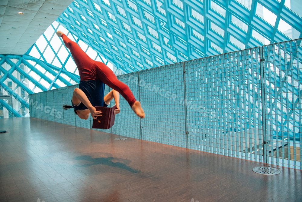 Woman jumping and reading a book inside the Seattle public library