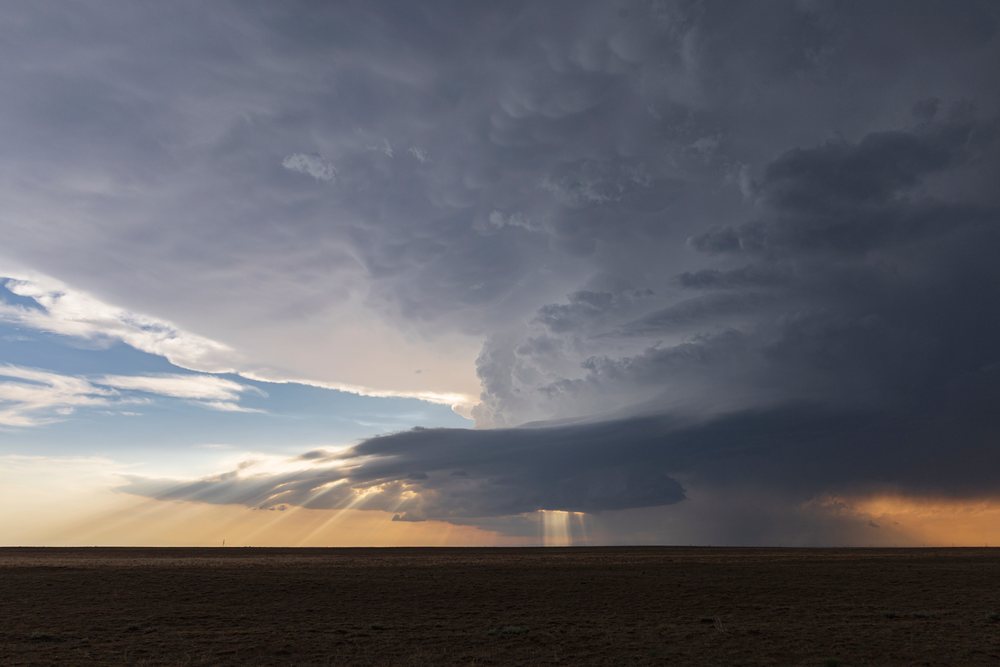 Developing Storm clouds cast sunlight rays over an open plain in the Midwest Tornado Alley, Storm Chasing, Weather, Environment, Olney Springs, Colorado, USA.
