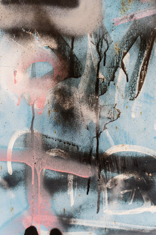 Abstract colorful spray paint patterns and rust spots on a weathered blue metal surface with paint drips and smudges, texture, abstract texture, background, wallpaper, Spain.