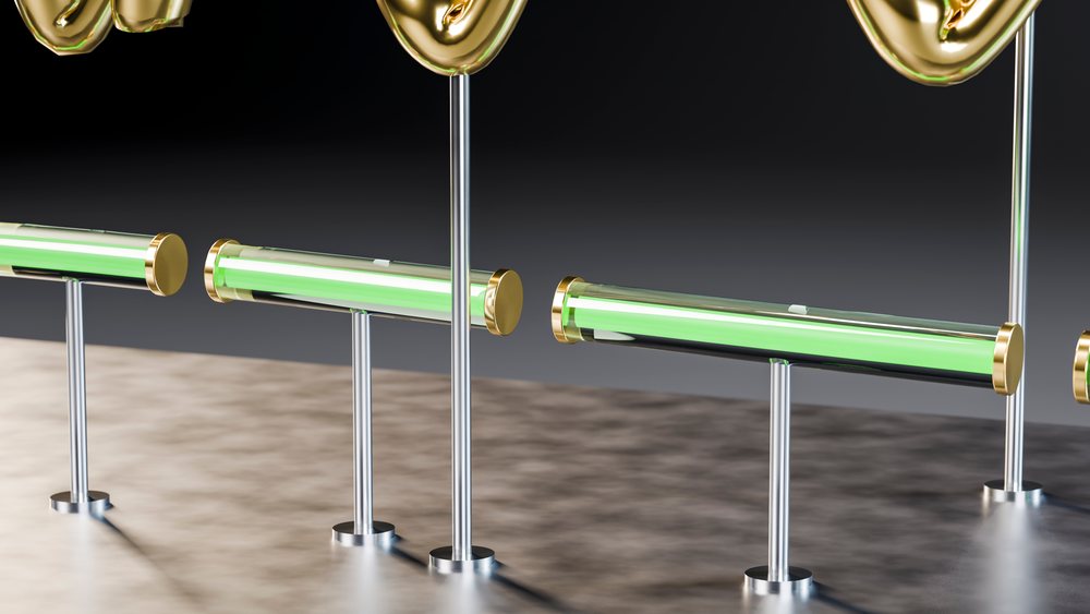 Green neon light tubes with gold and chrome accents on metal stands displayed on a reflective surface against a black background.