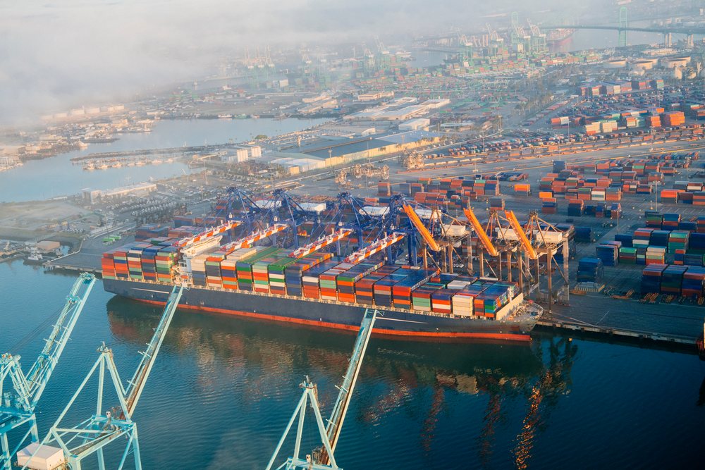 Container ship loaded with colorful shipping containers docked at cranes in the Port of Long Beach, California, CA, USA.