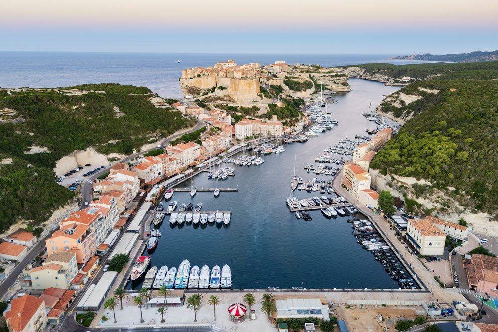 The historic Citadel overlooking Bonifacio's Inner Harbour with docked boats at dawn along the Mediterranean coastline, Travel Photography, Corsica, France.