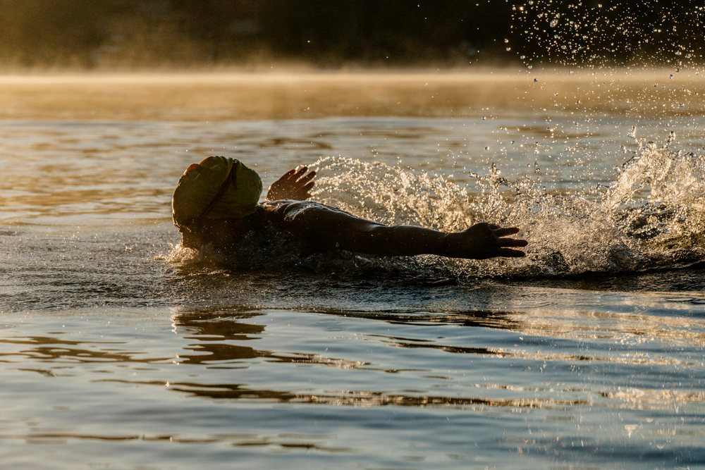 Swimmer performing freestyle stroke in open water at early morning in the USA with water splashing around.