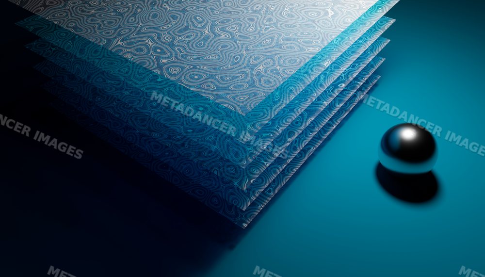 Stack of patterned papers with a metal reflective ball on blue surface