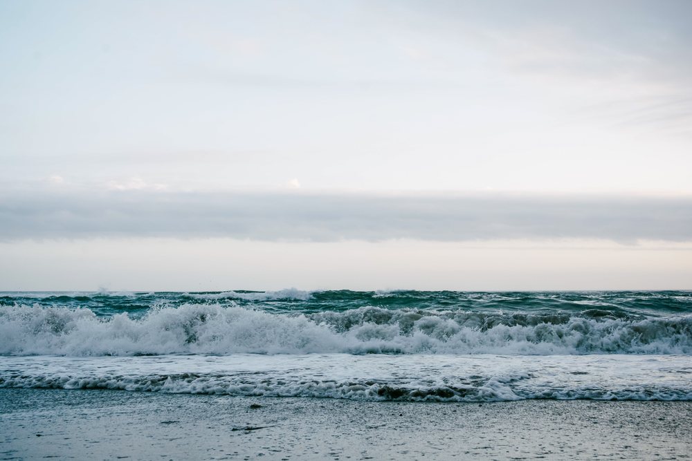 Ocean waves breaking with foam under a cloudy sky along the shore, Spain.