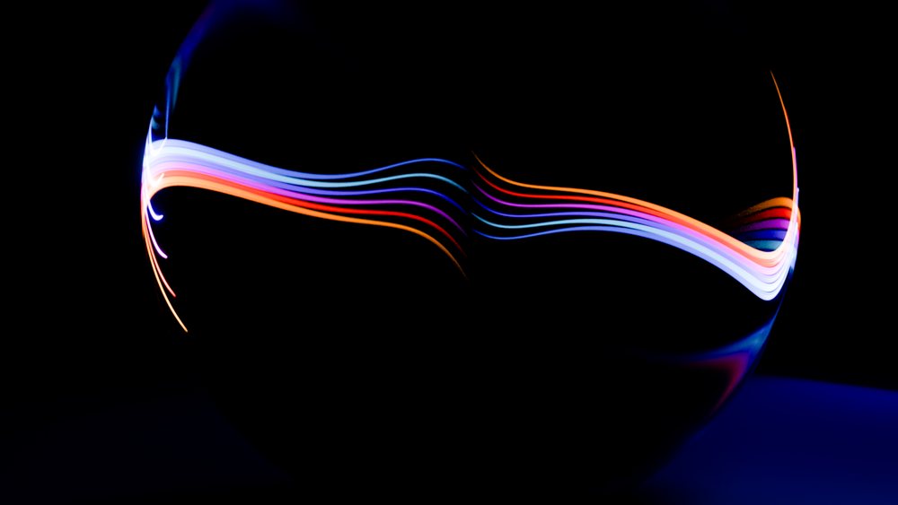 Colorful curved light trails glow against a dark background in an abstract digital art illustration.