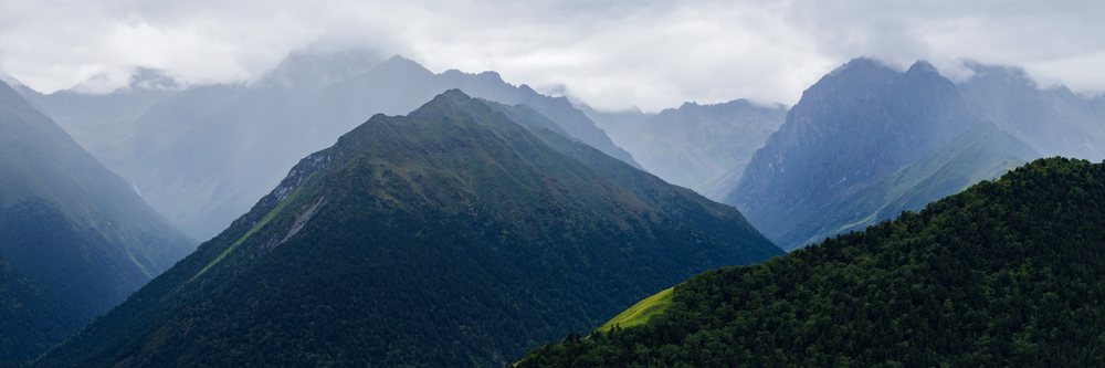 Belang Mountains feature forested slopes and cloudy mountain peaks, Sichuan Province, People's Republic of China.