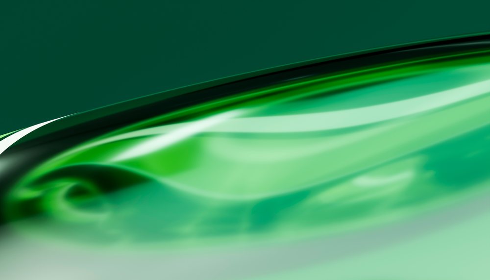Green liquid wave with smooth glossy surface and fluid motion against an abstract background.