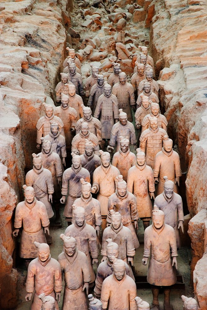 Terracotta Warriors arranged in rows within an archaeological excavation trench, Shaanxi Province, China.