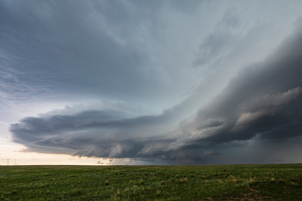 Supercell storm forming over a green grassy plain with dramatic dark clouds and open landscape, Pine Bluffs, Wyoming, USA.