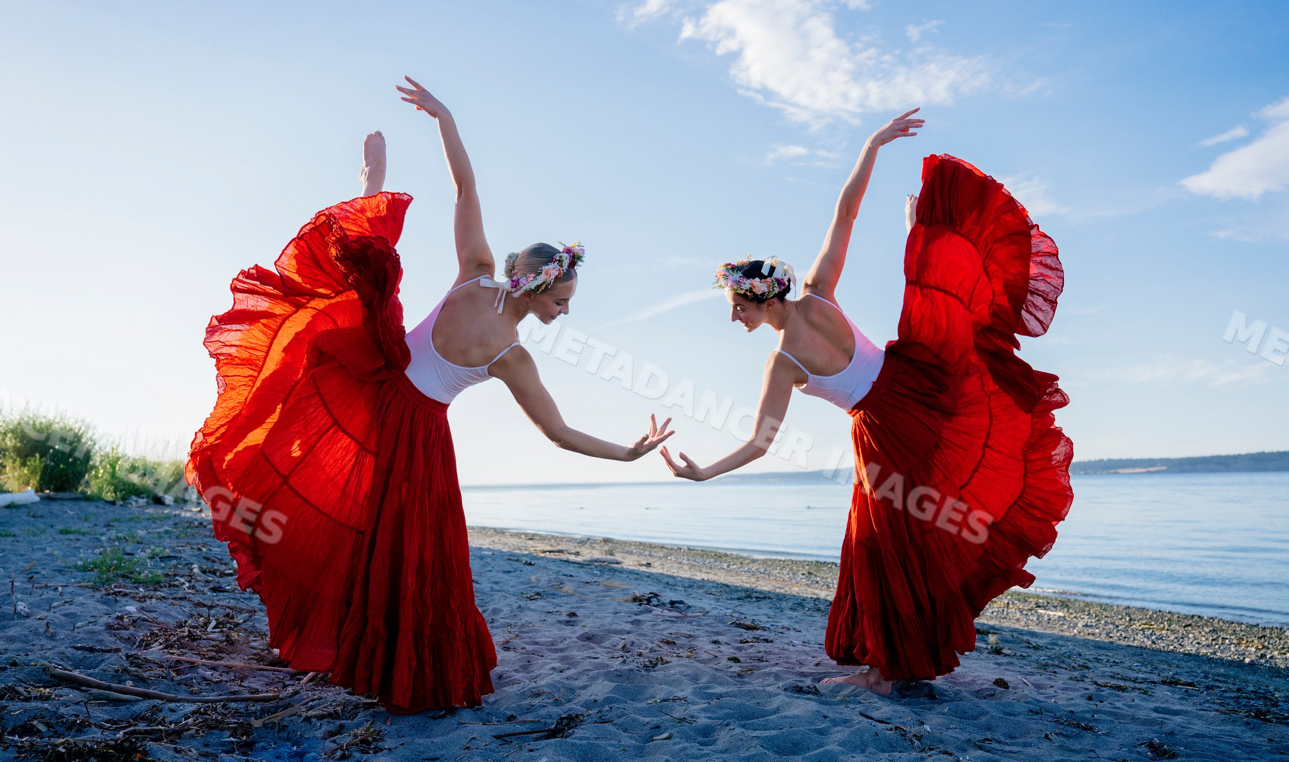 Two white women perform partner yoga acrobatics on a beach in WA, USA