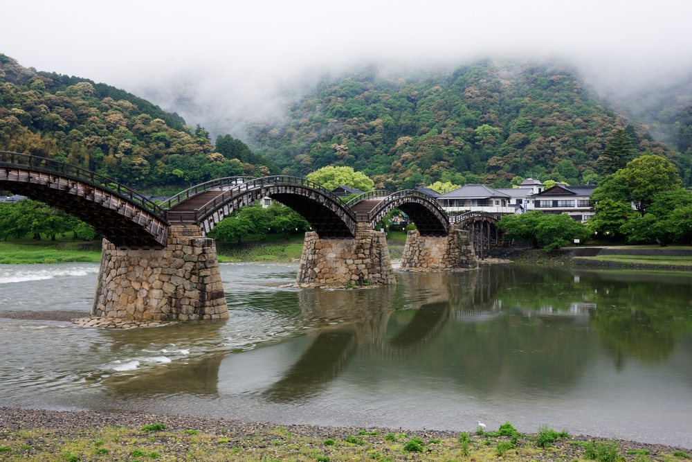 Kintai bridge spanning a foggy river with mountains, japan