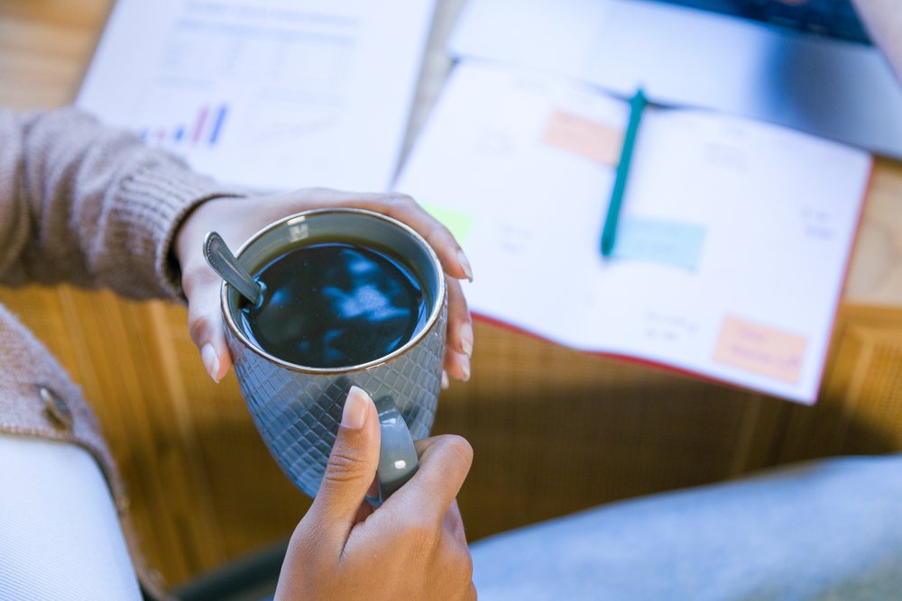 African American person holding coffee mug and working