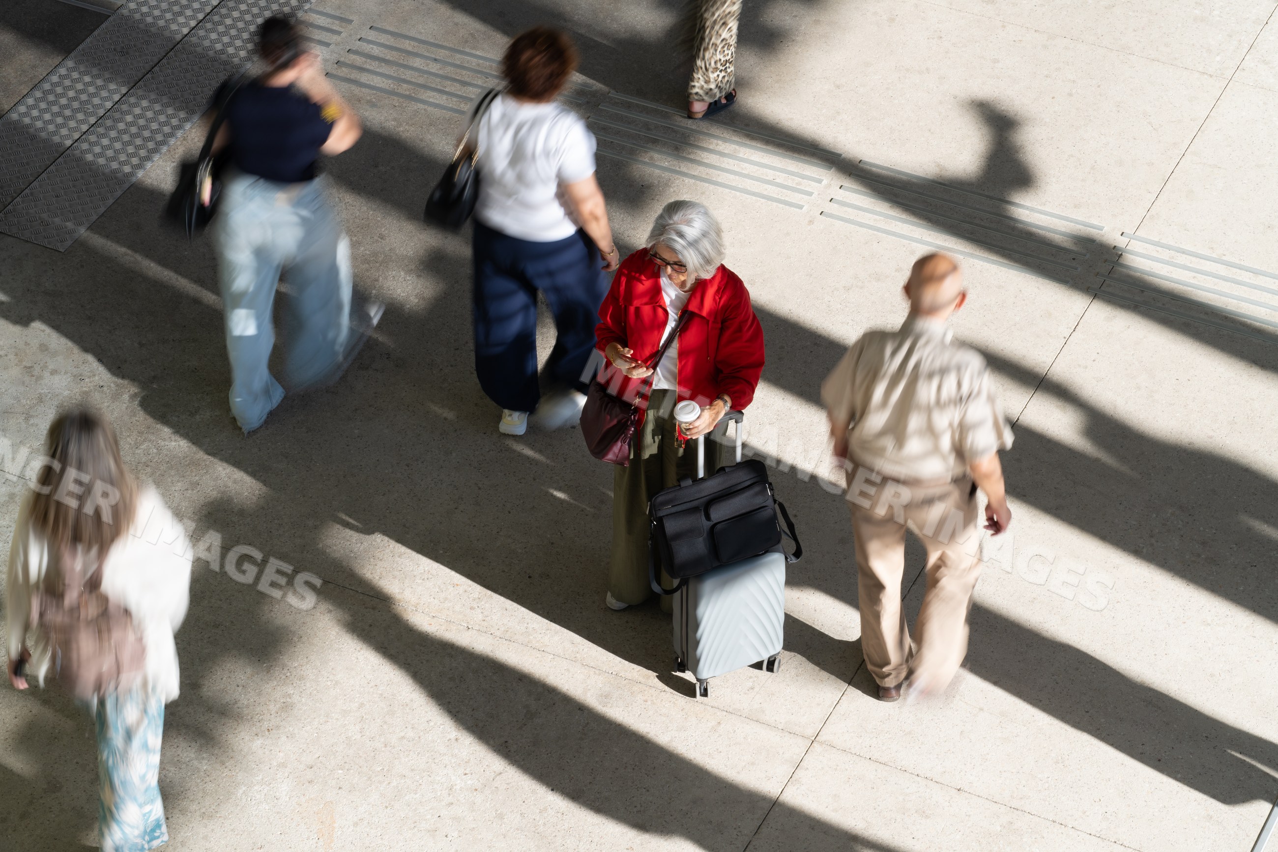 Traveling white woman with rolling suitcase amidst pedestrians
