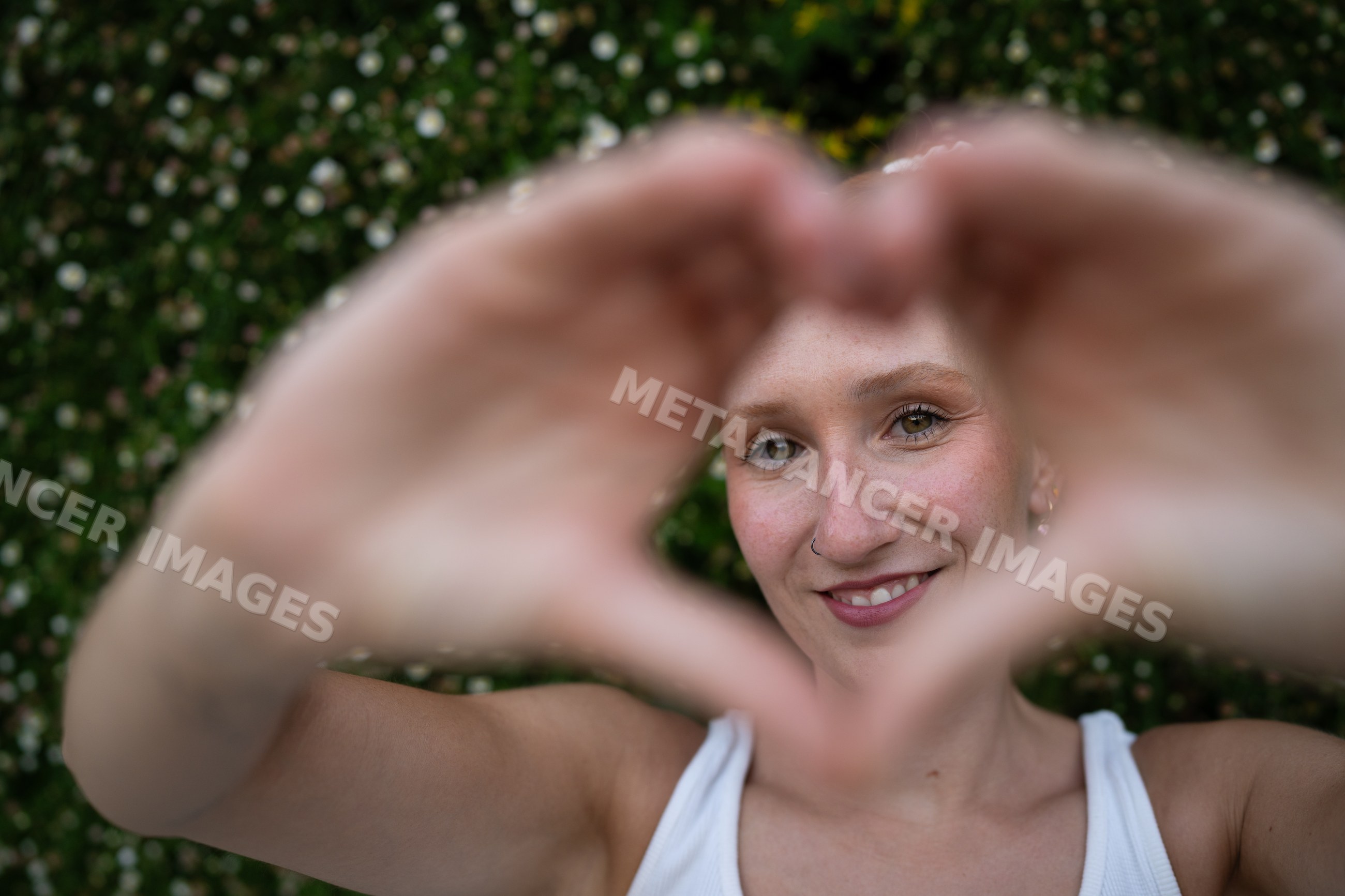 A white woman forms a heart shape with her hands