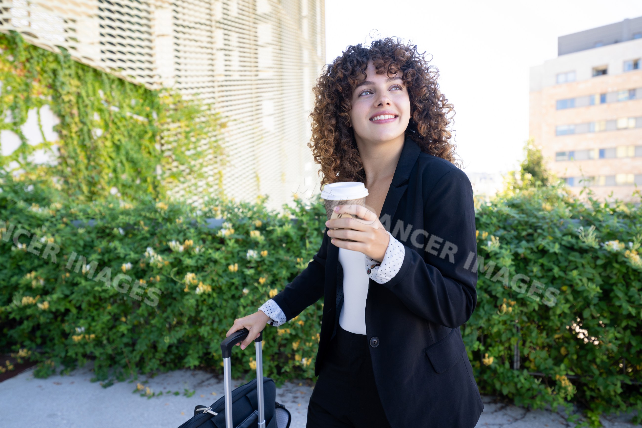 White woman holding coffee cup with rolling suitcase