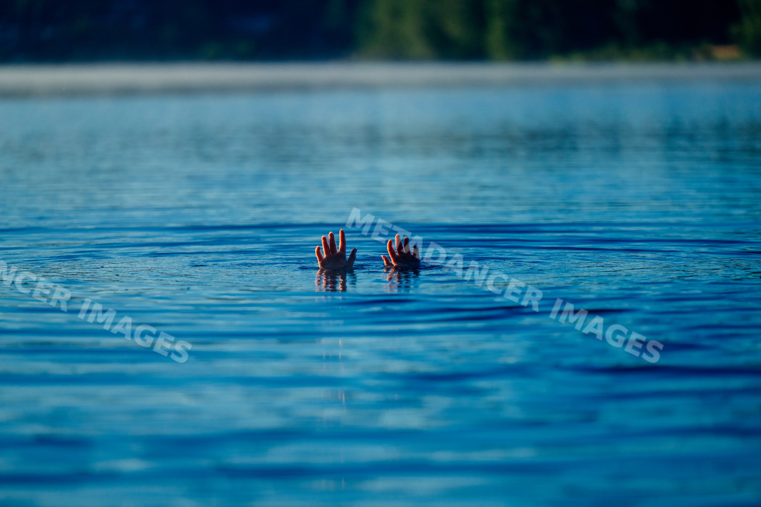 Hands raised above calm lake water surface