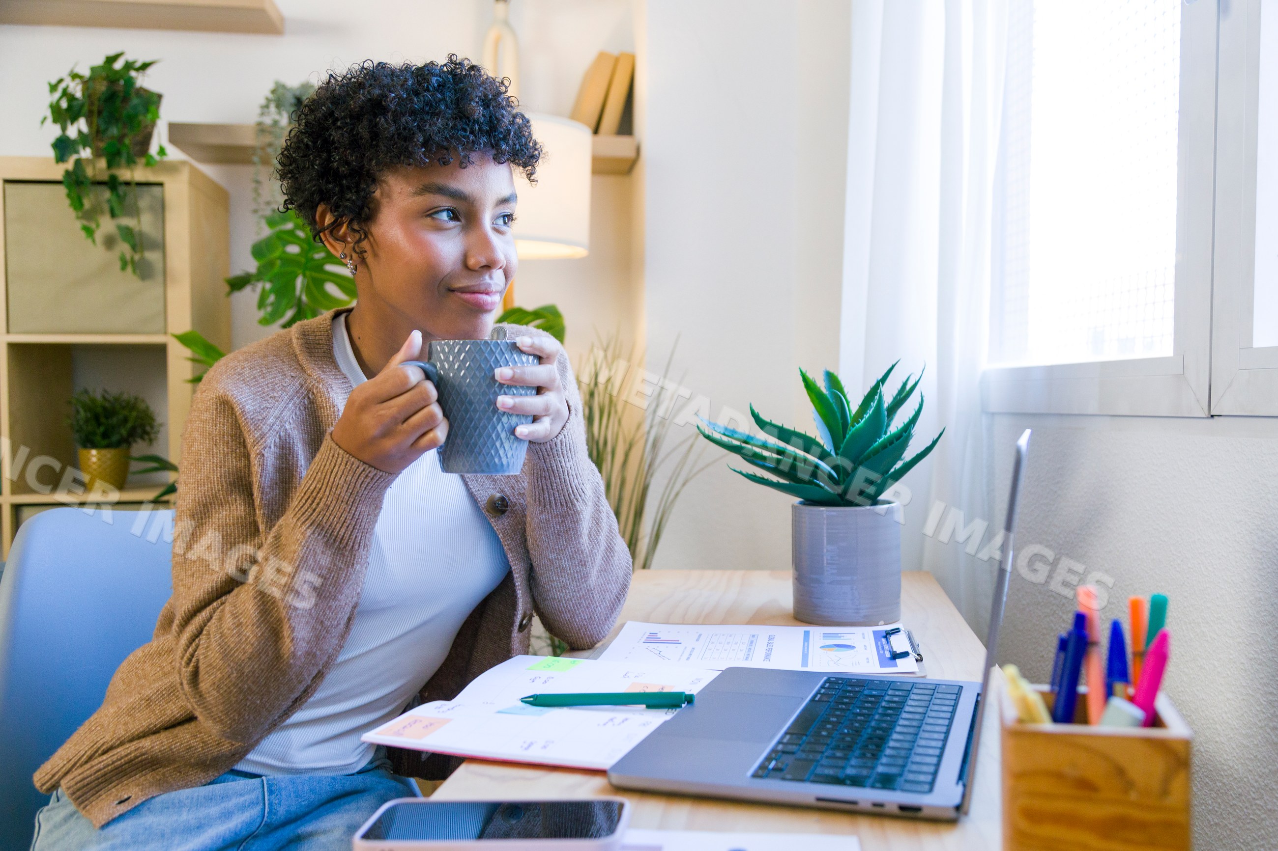 African American woman drinking coffee at desk in home office