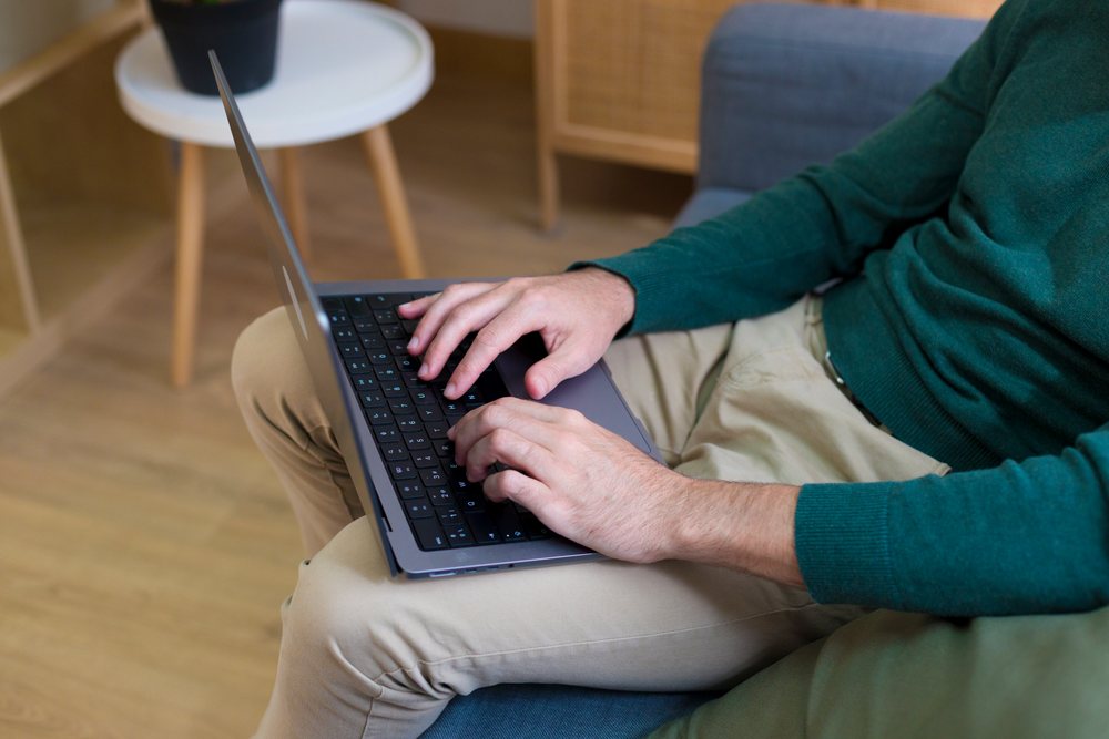 White man typing on laptop in living room indoors