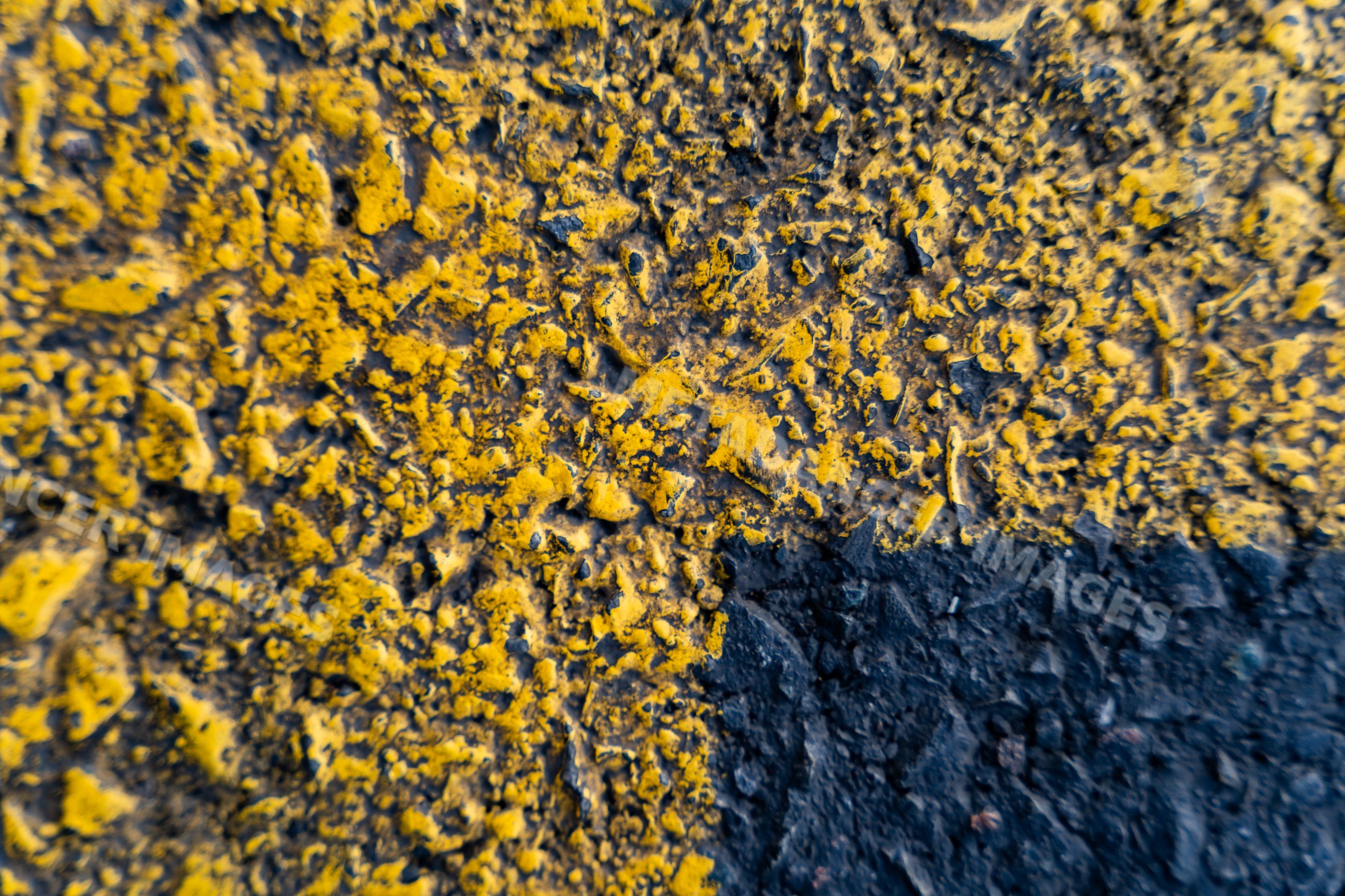 Close-up of rough textured yellow and black asphalt road markings