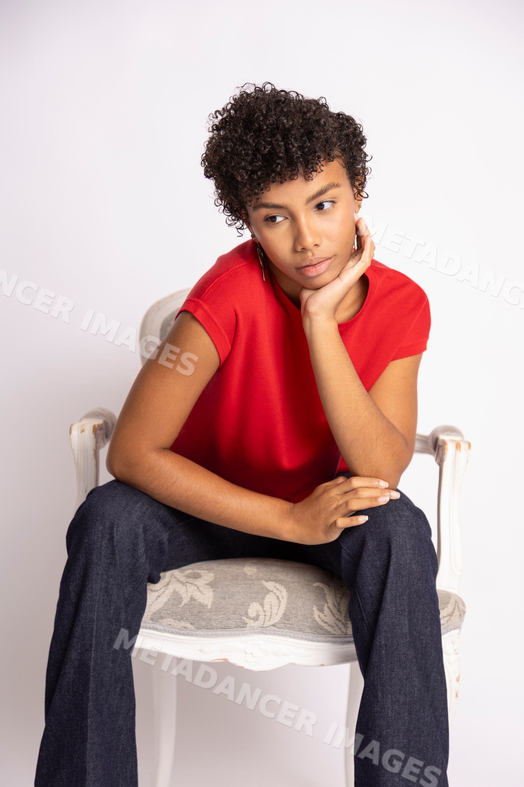 Hispanic woman sitting thoughtfully in red shirt and blue jeans