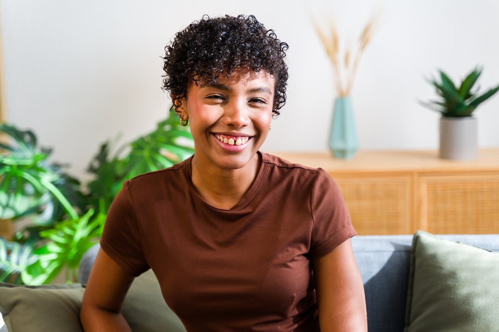 Smiling African American woman with curly hair sitting on sofa