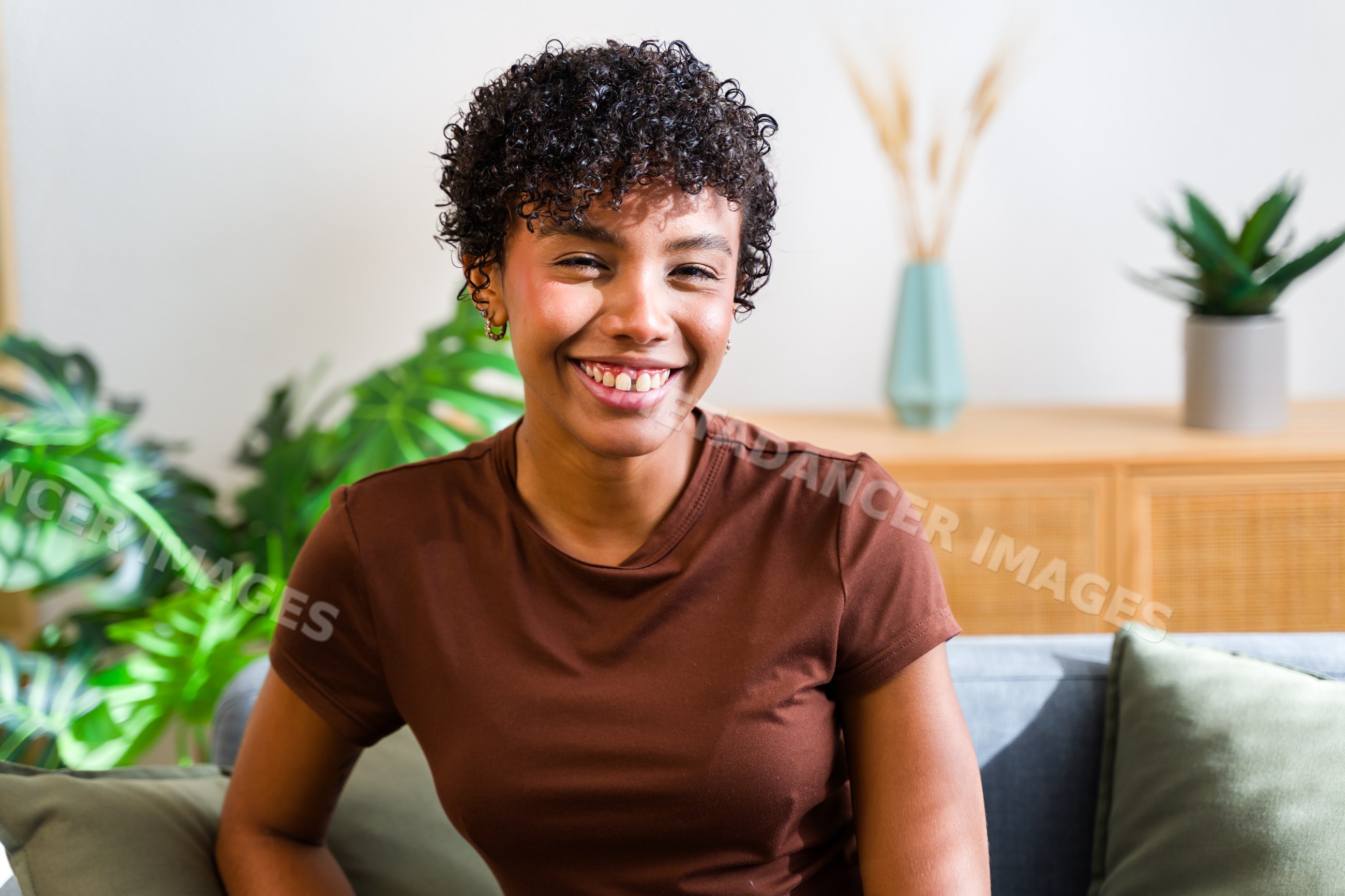 Smiling African American woman with curly hair sitting on sofa
