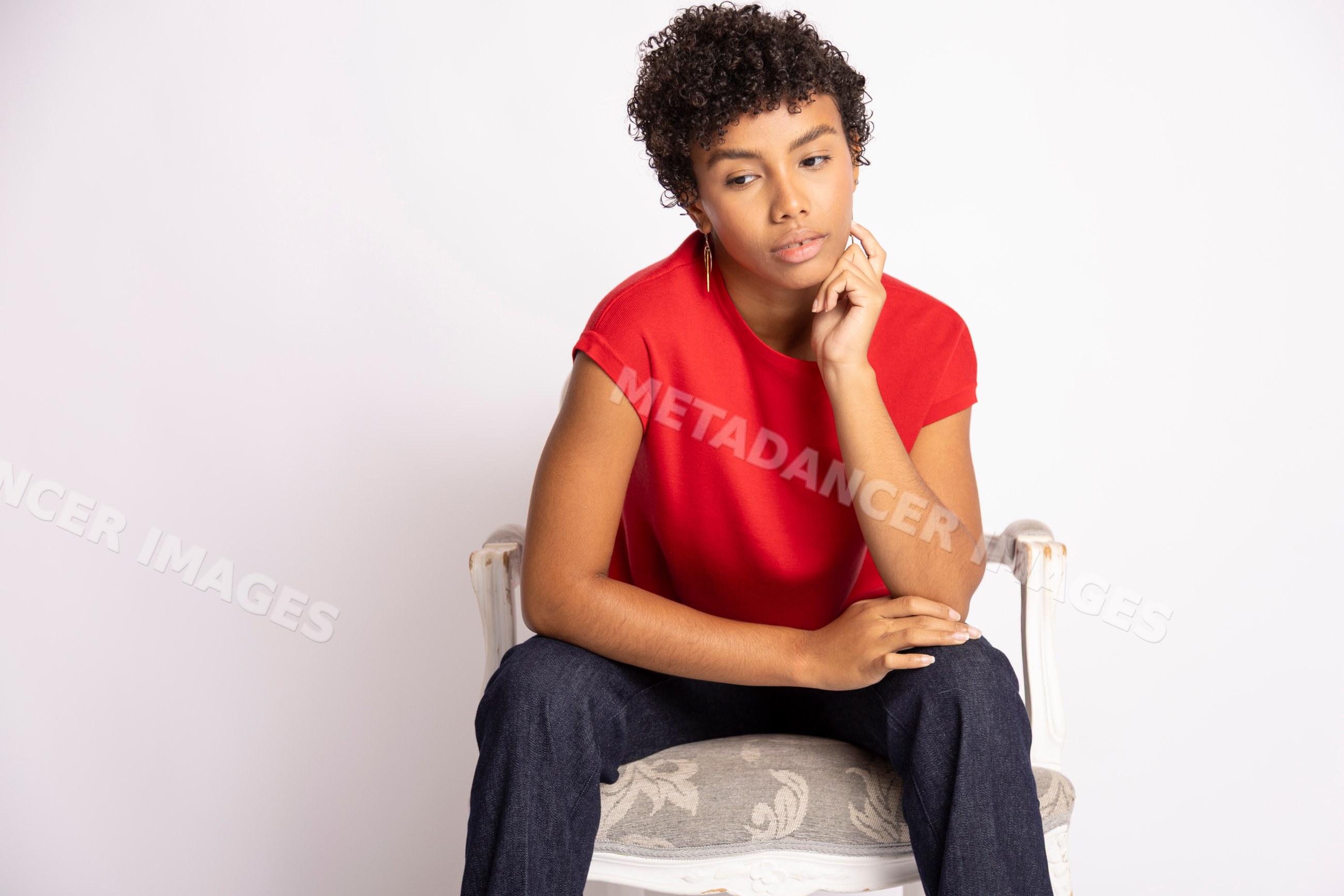 Hispanic woman sitting thoughtfully on upholstered chair