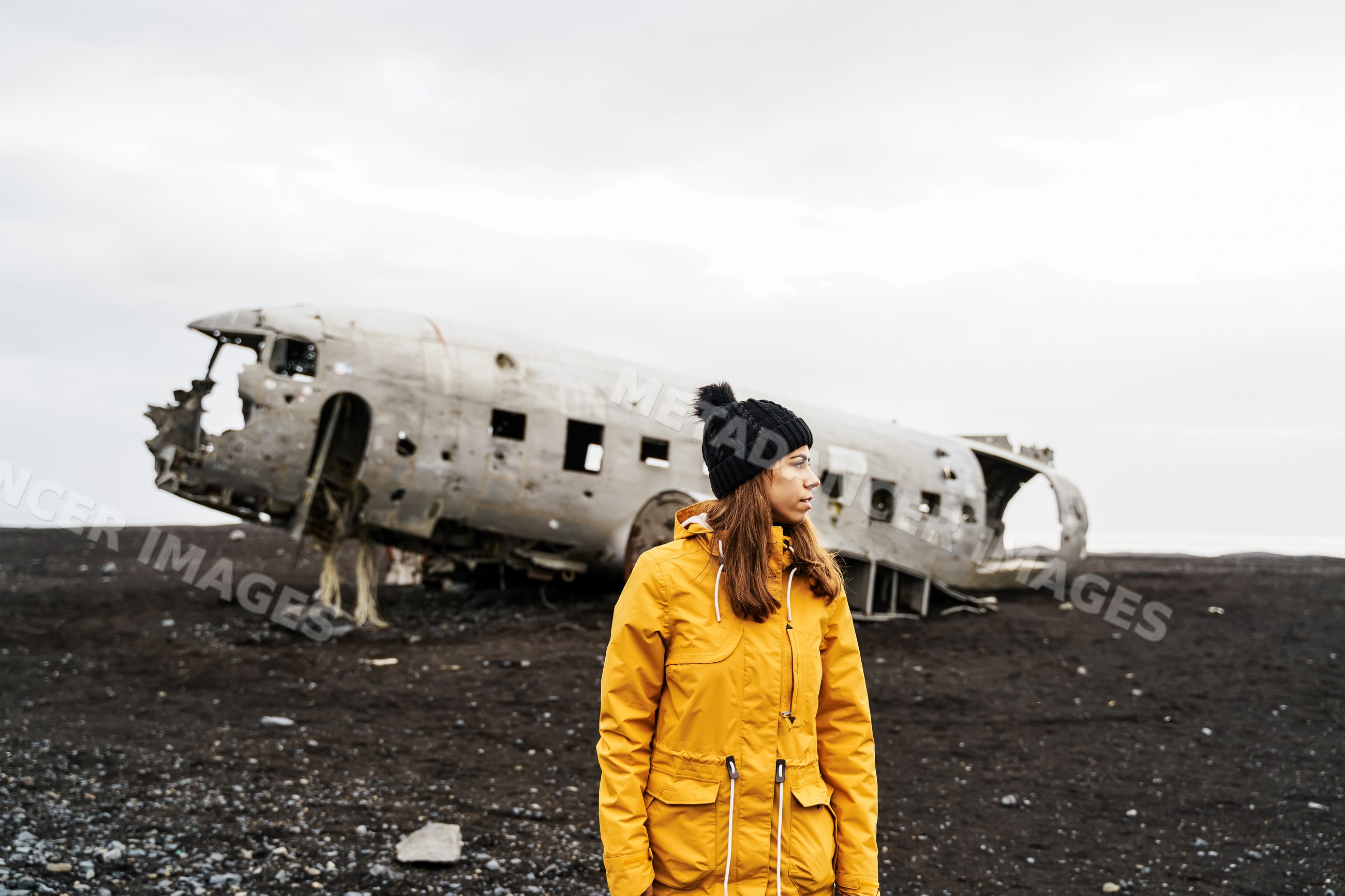 A white woman stands by an abandoned aircraft wreck on Iceland's