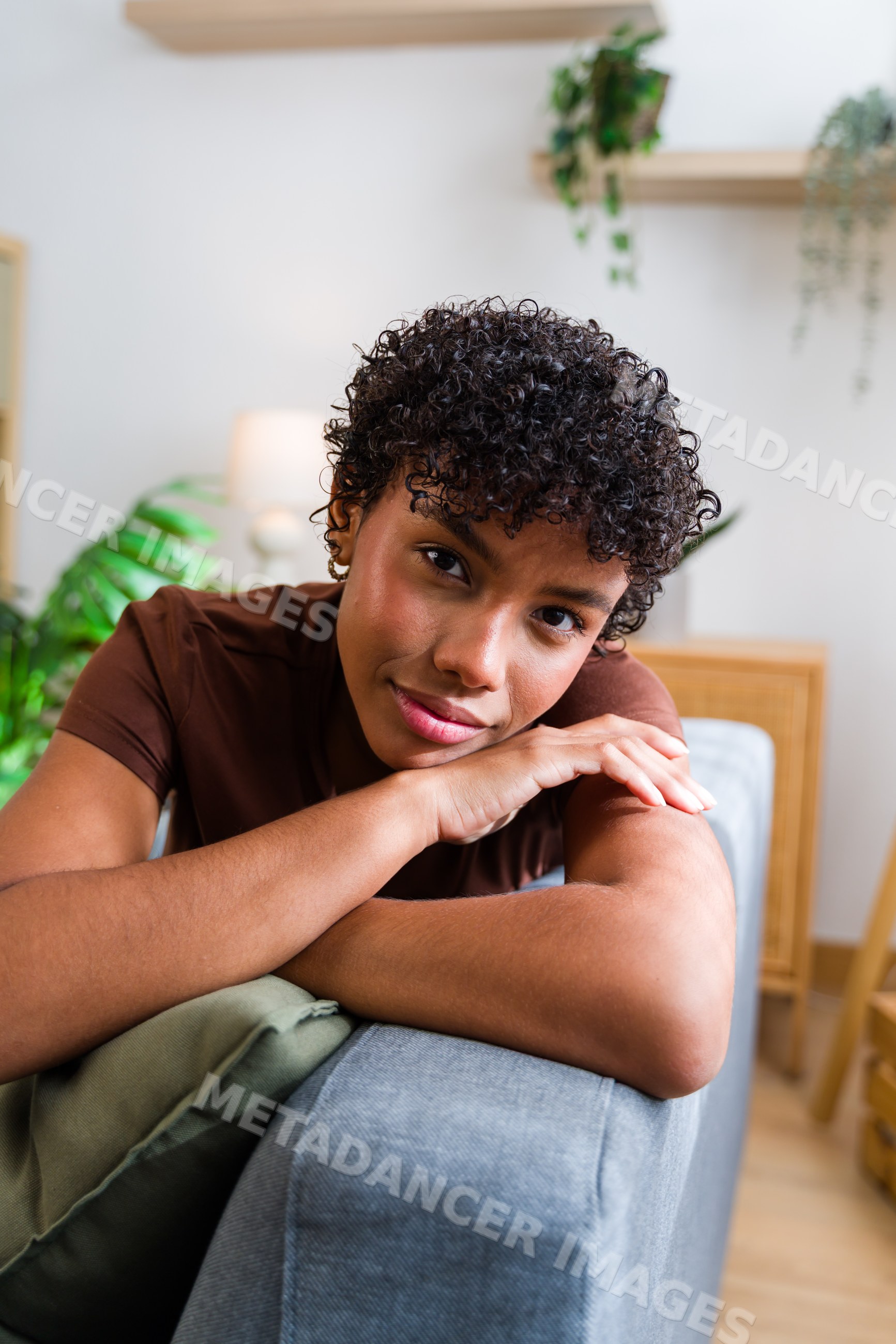 African American woman with curly hair resting on grey sofa