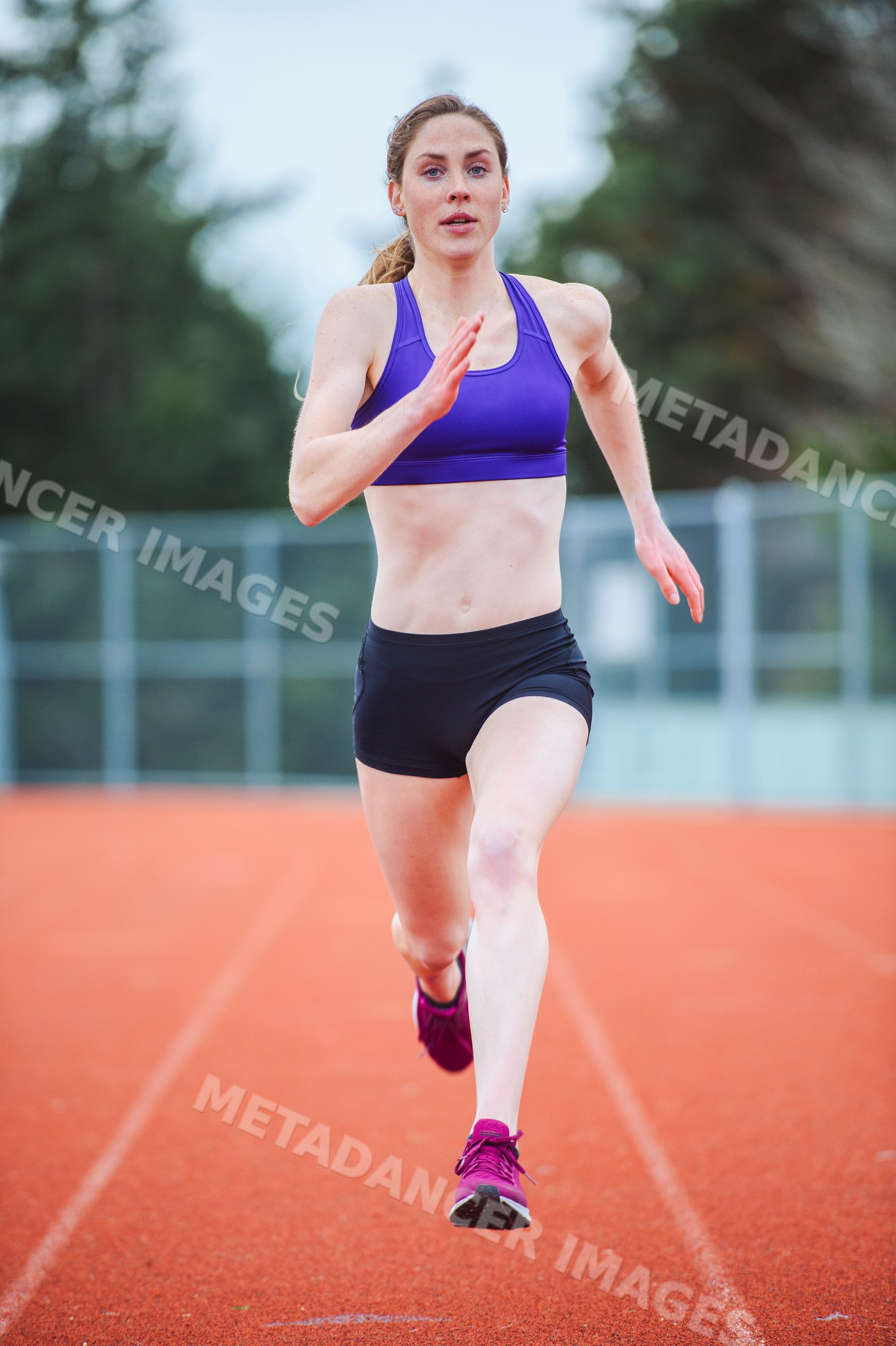 White female athlete running on outdoor track in sportswear
