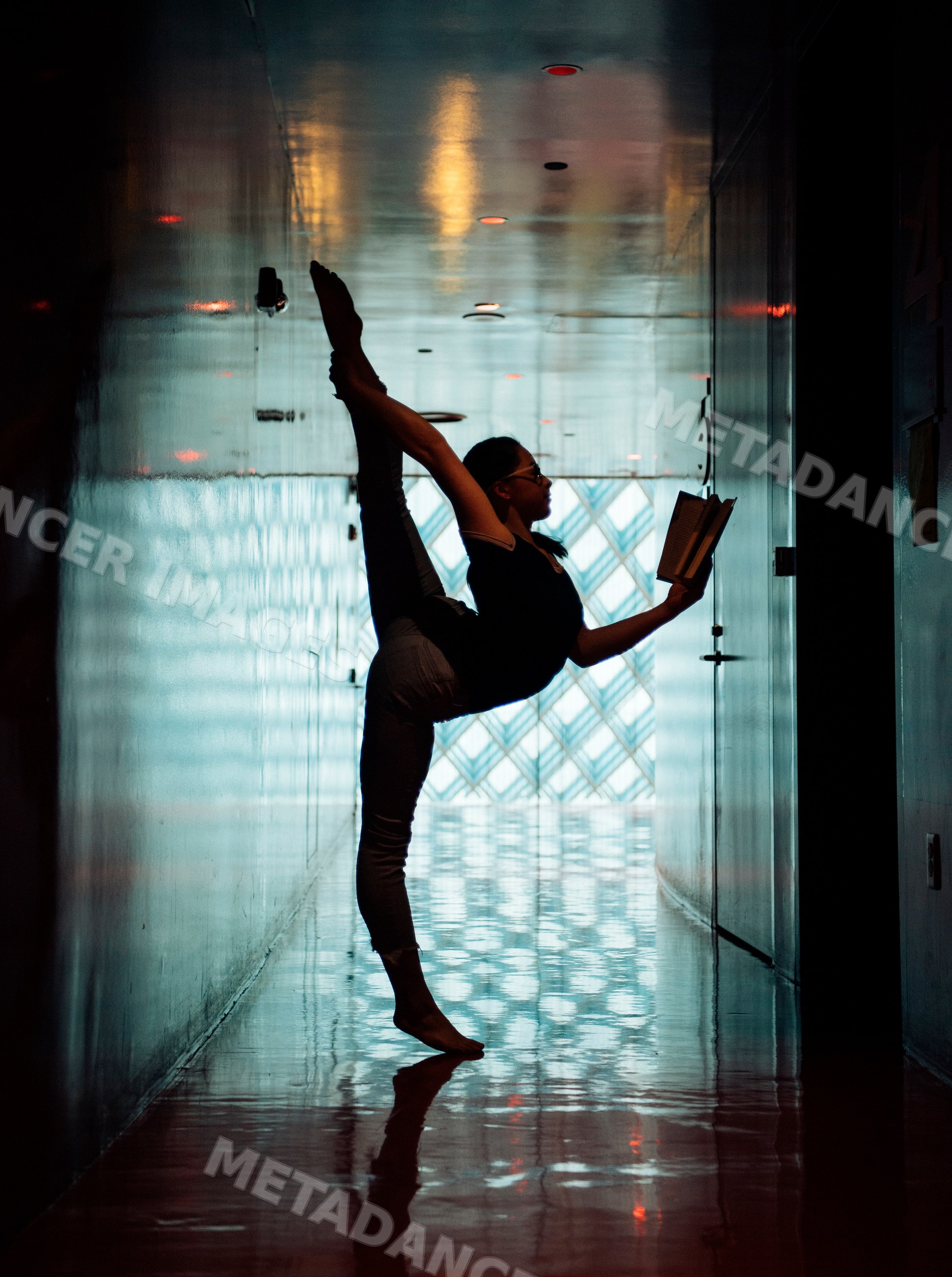 A girl stretches in a yoga pose while reading a book in a library