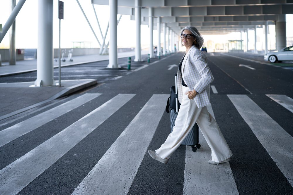 Businesswoman walking with rolling luggage at airport terminal