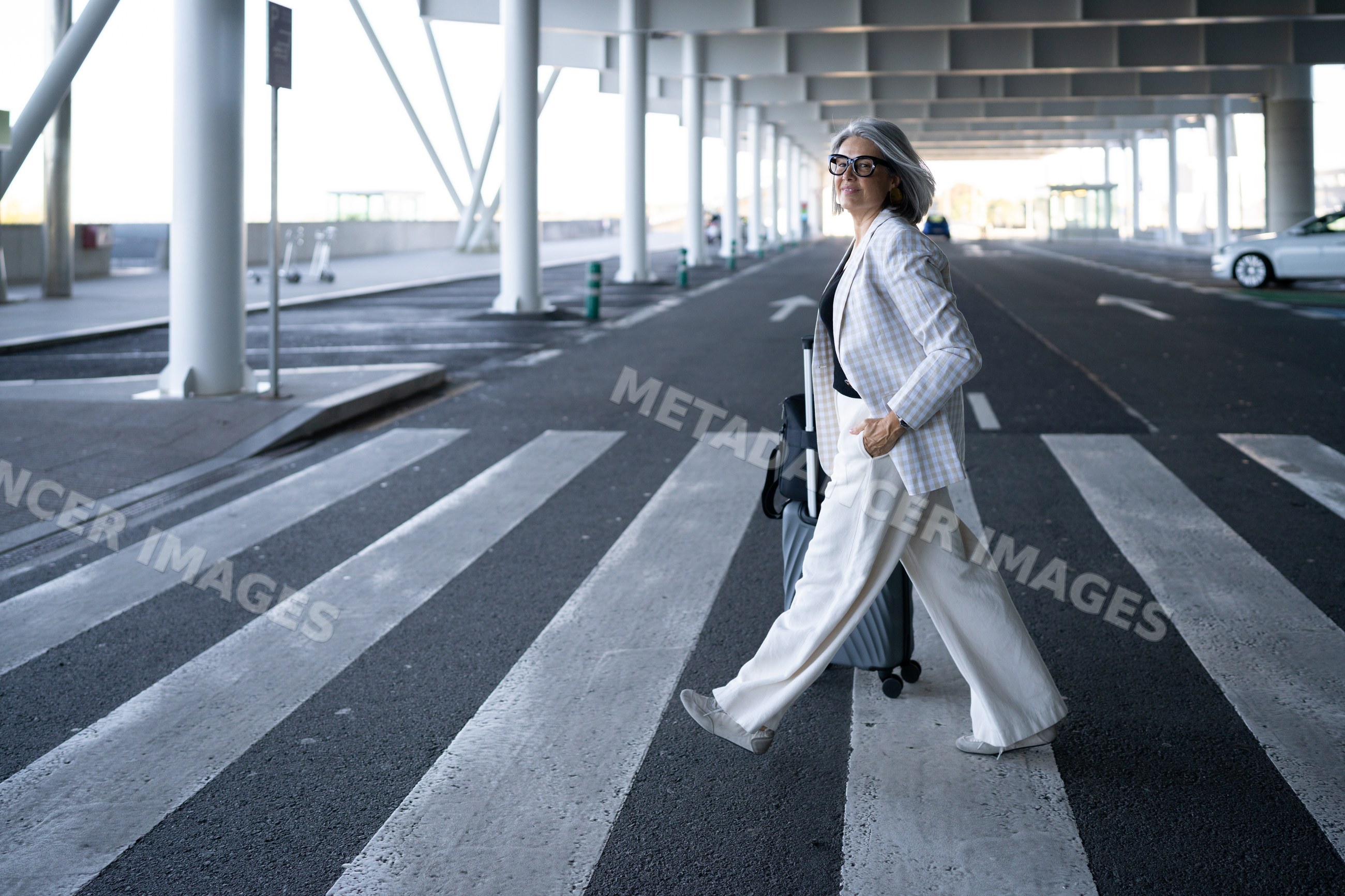 Businesswoman walking with rolling luggage at airport terminal
