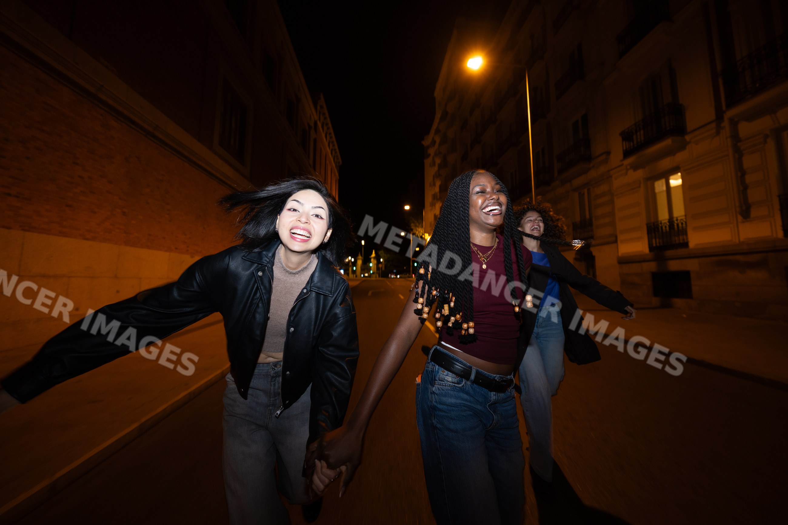 Three Hispanic, white and Black women laughing and running together