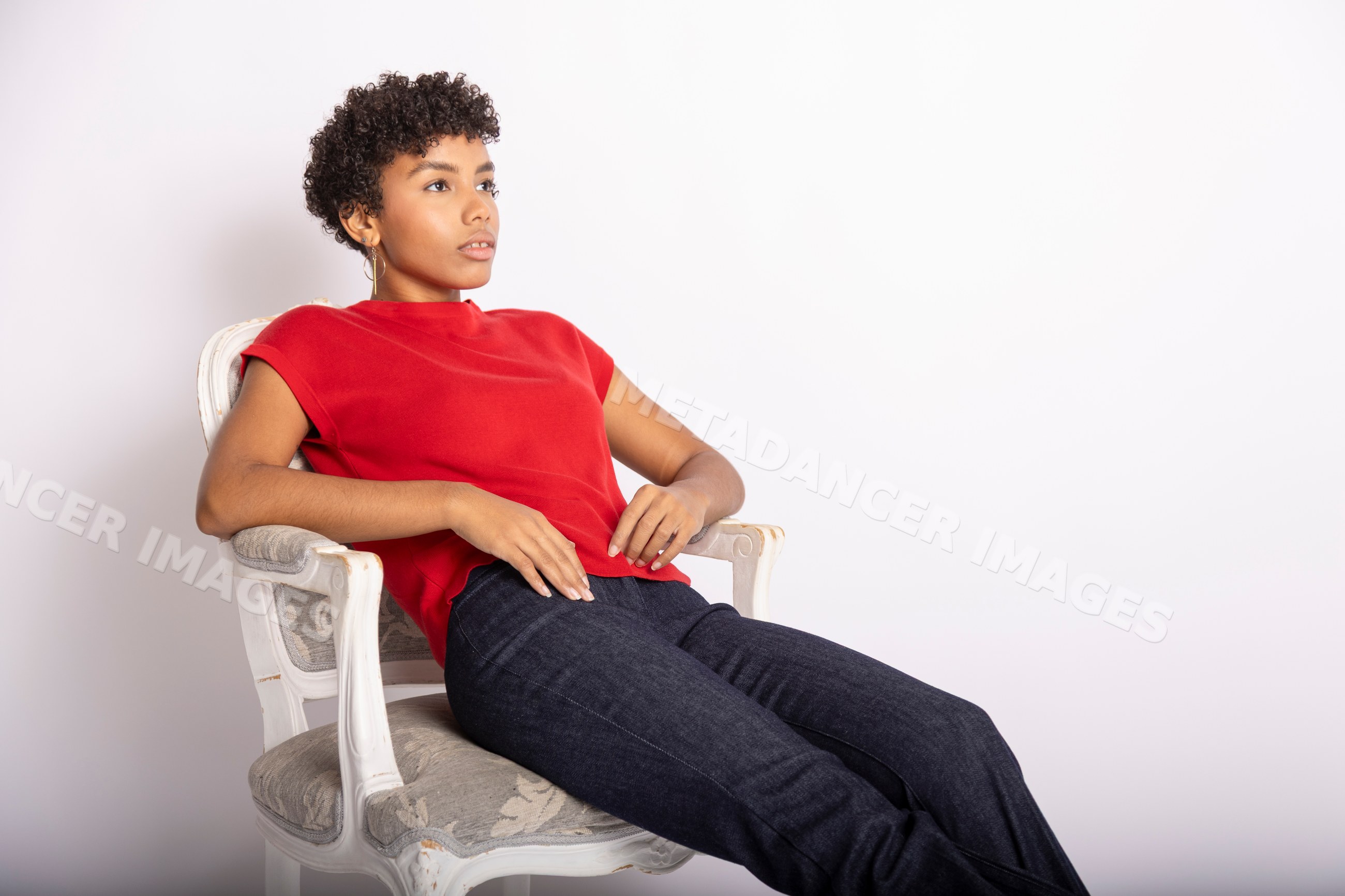 Hispanic woman sitting relaxed in a red top and dark jeans