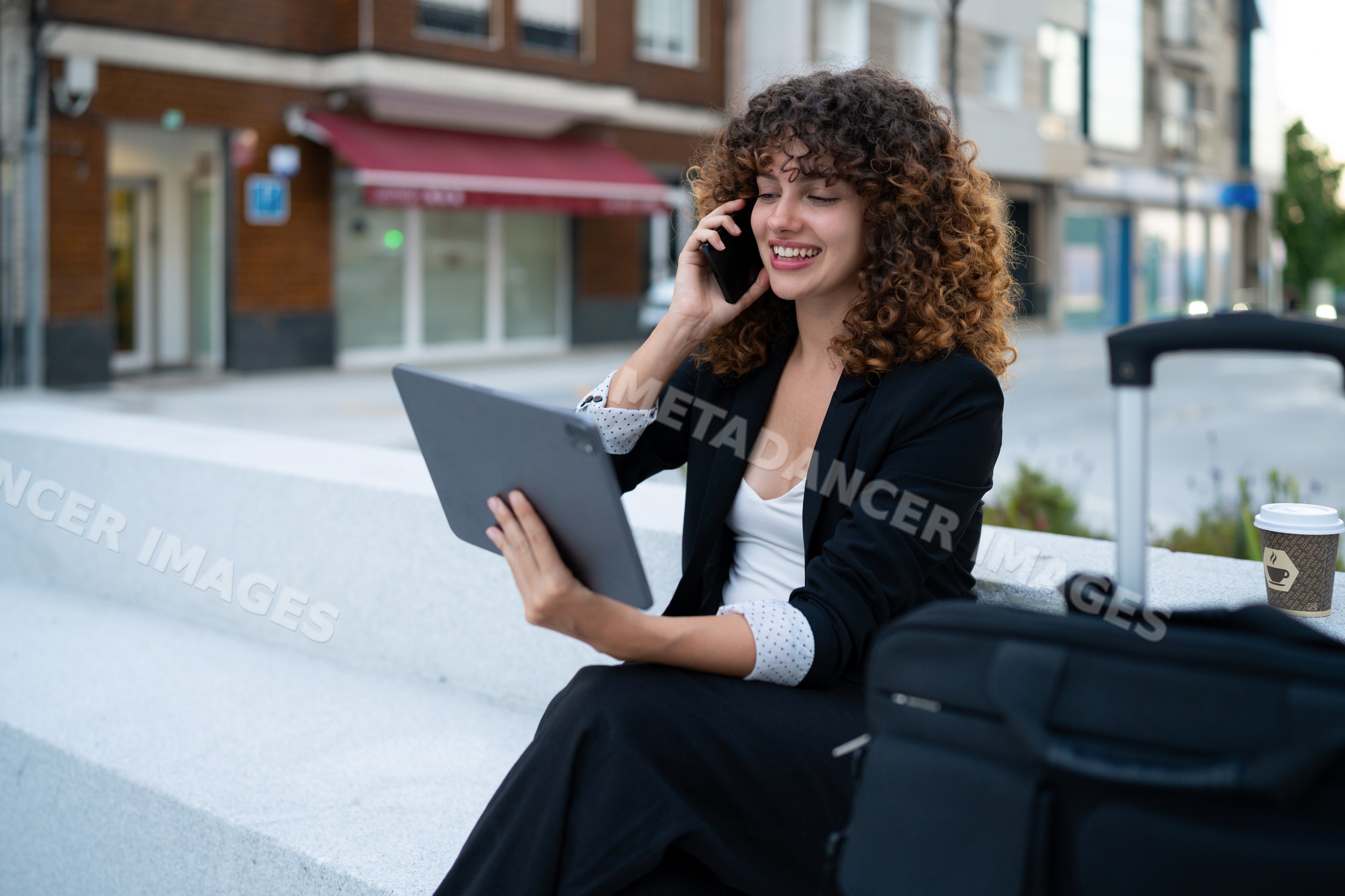 Business white woman using tablet and phone while waiting outdoors