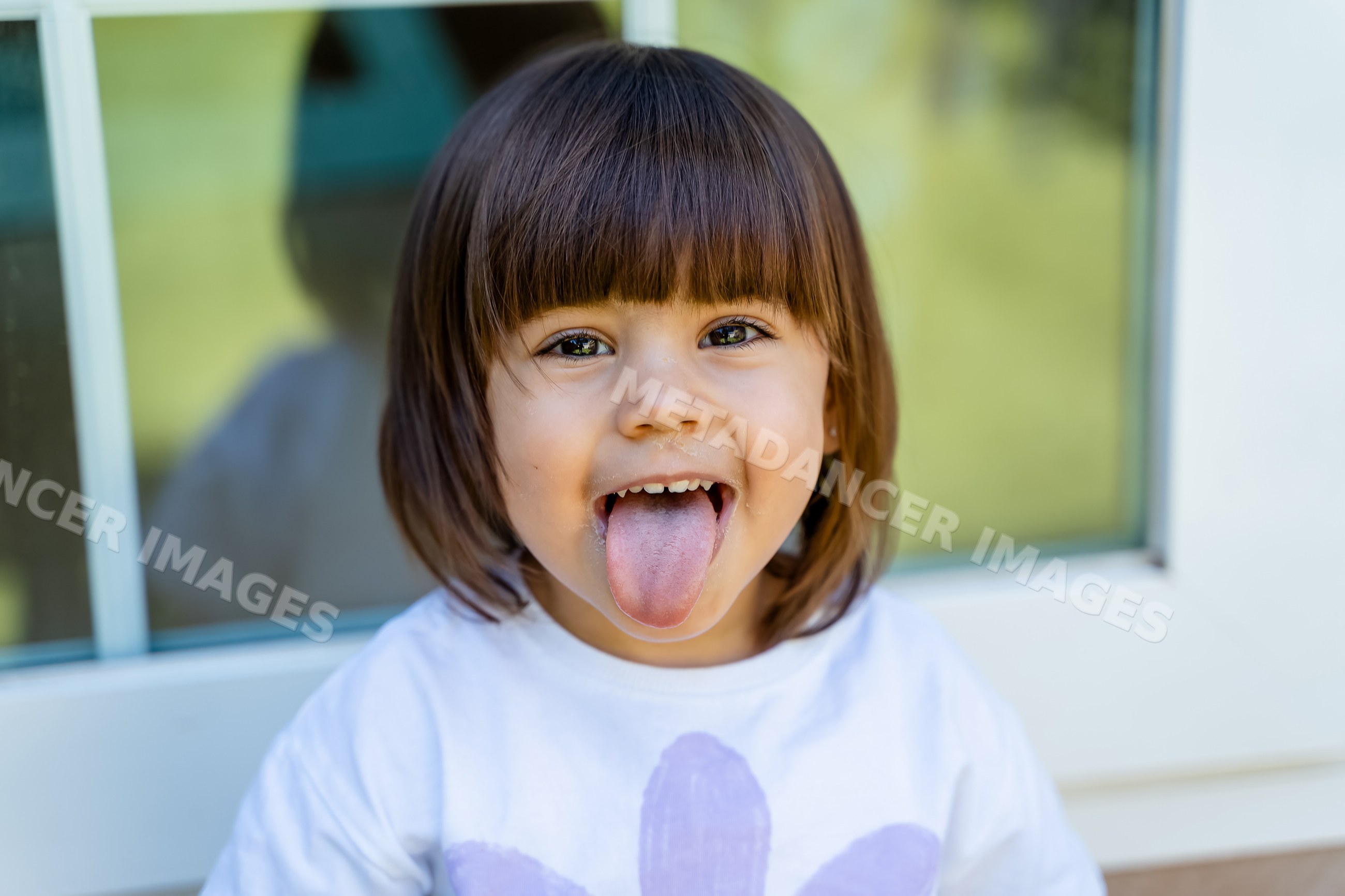White child smiling and sticking out tongue outdoors
