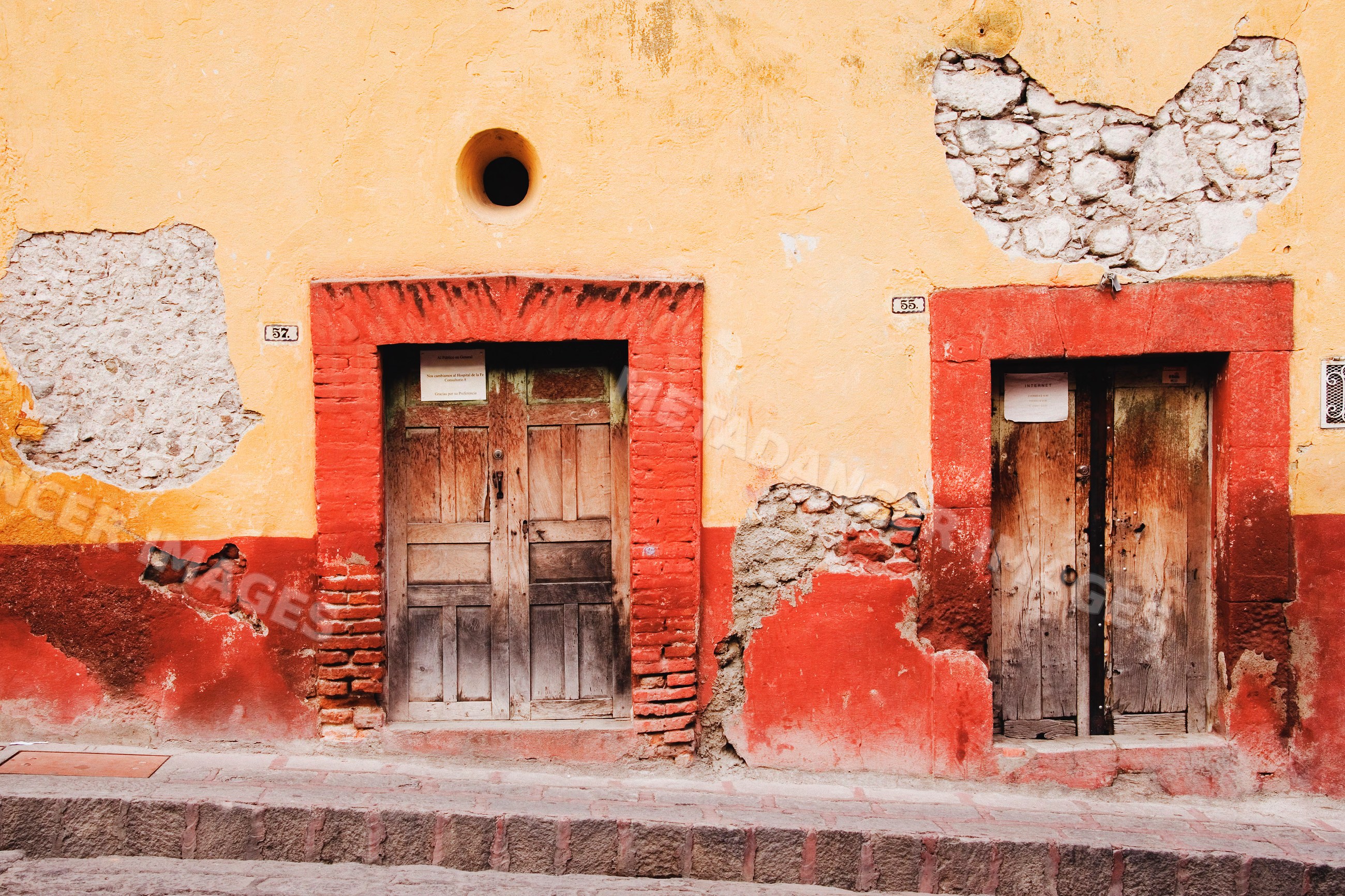 Two weathered wooden doors on yellow and red wall mexico