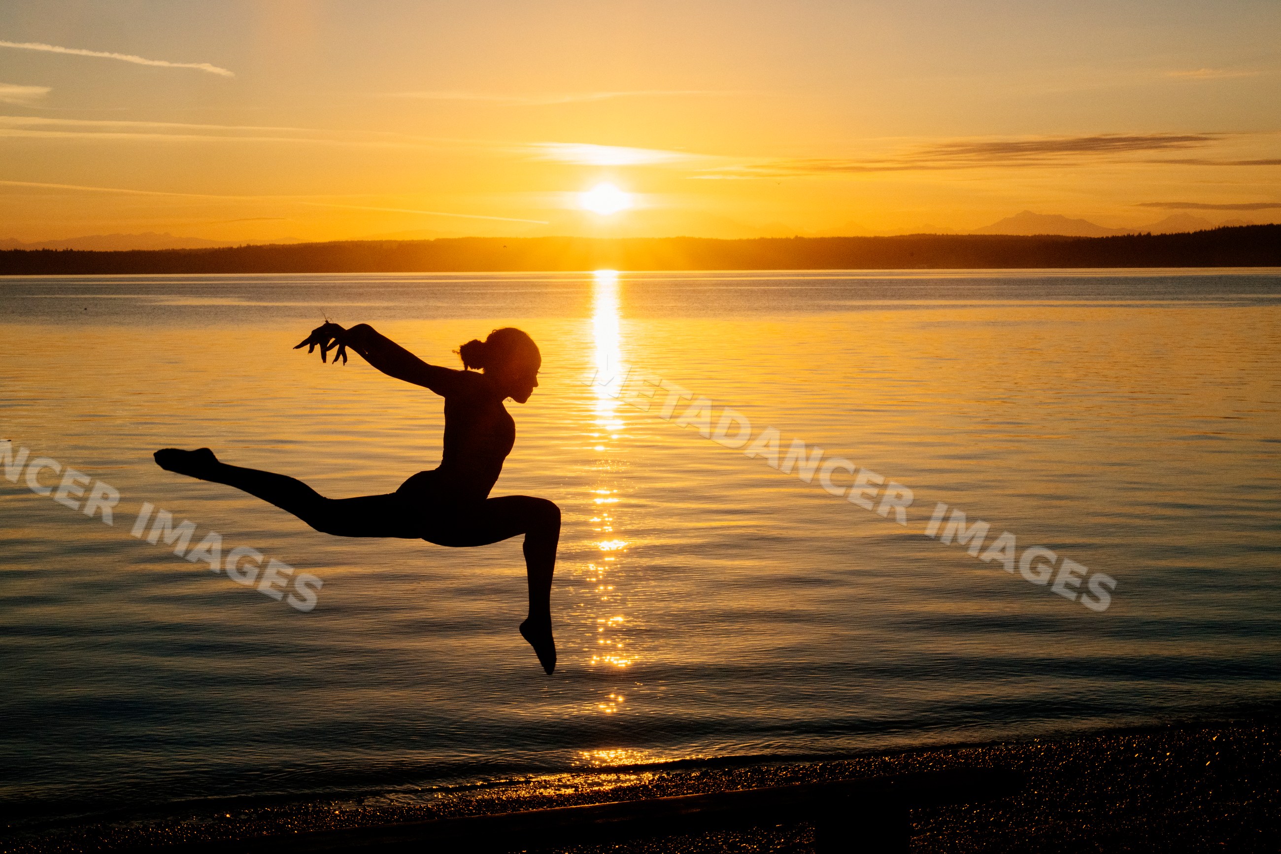 Silhouette of Hispanic dancer leaping at sunset by water